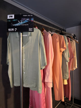 Clothing rack with various shirts hanging on it against a dark wall.