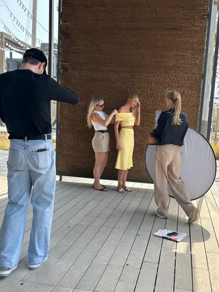 Person taking a photo of three women on a wooden deck with a circular mirror.